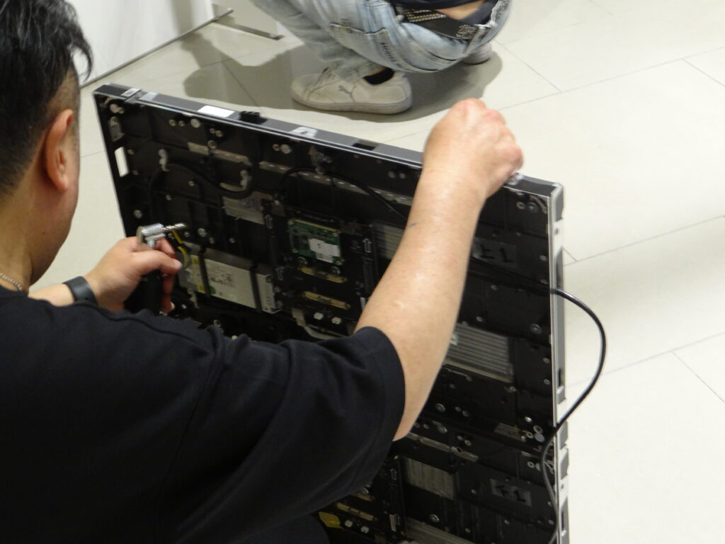 LEDパネル内部からビスを差し込み台座に取り付ける作業